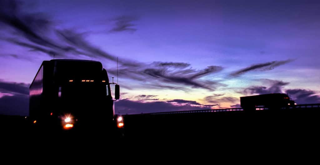 Trucks on road at sunset